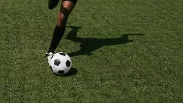 piłkarz prowadzący piłkę po zielonej murawie